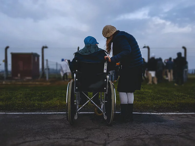woman checking on elderly person in wheelchair