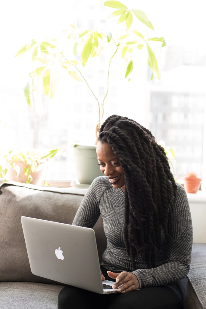 smiling young business woman sitting on sofa looking at laptop