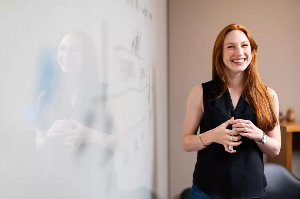 Woman smiling at a marker board.
