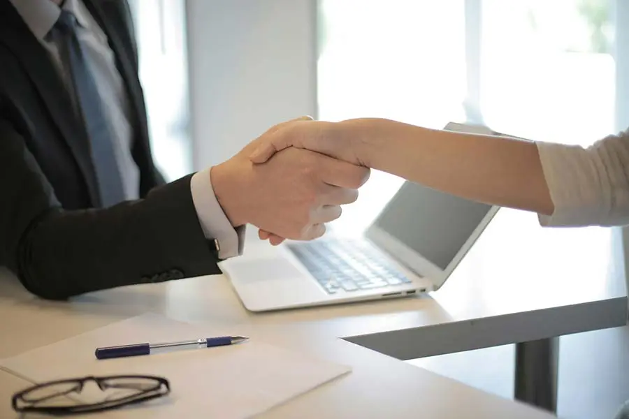 Two people shaking hands at a desk