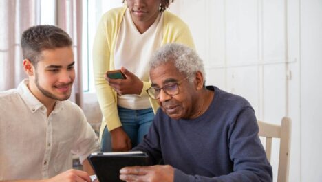 A caregiver shows an elderly man an electronic tablet